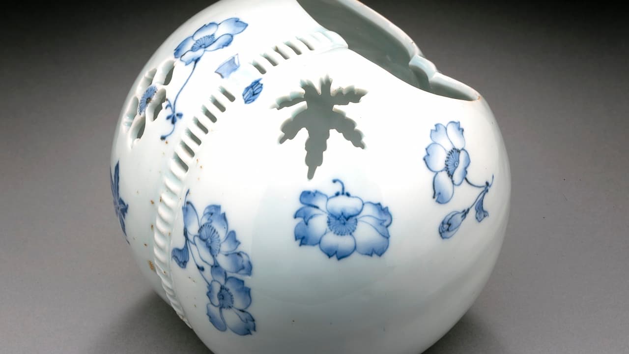 Porcelain hand warmer with blue floral motifs and carved vent openings