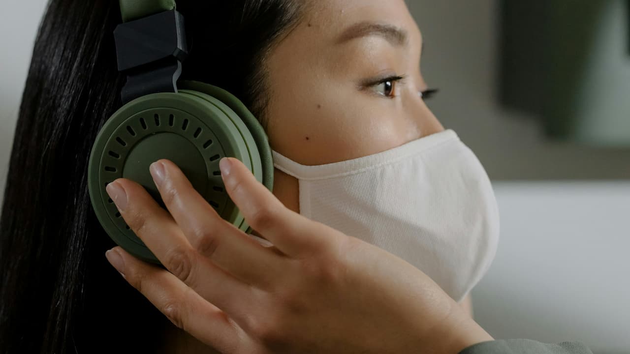 Person wearing green headphones and a white face mask
