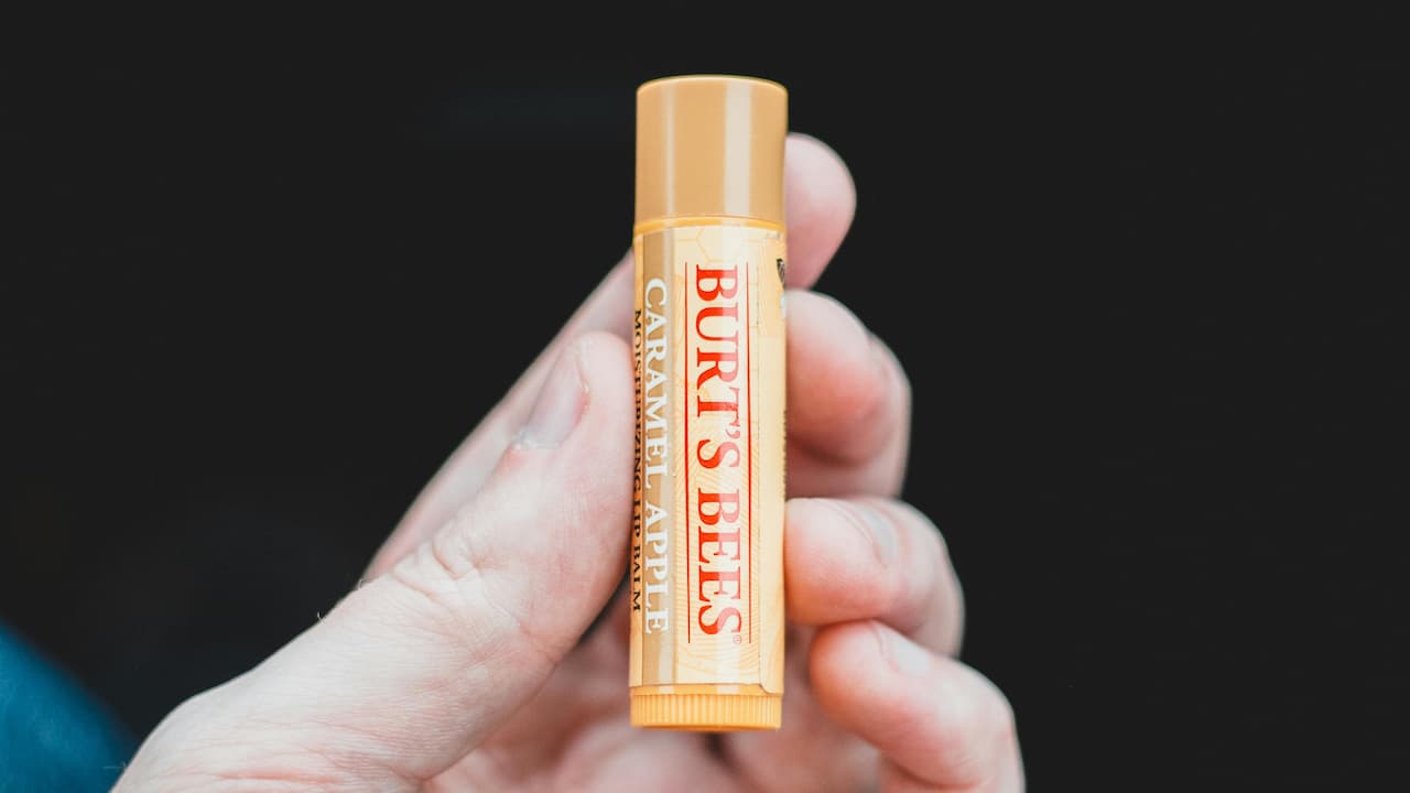 Hand holding Burt’s Bees caramel apple lip balm