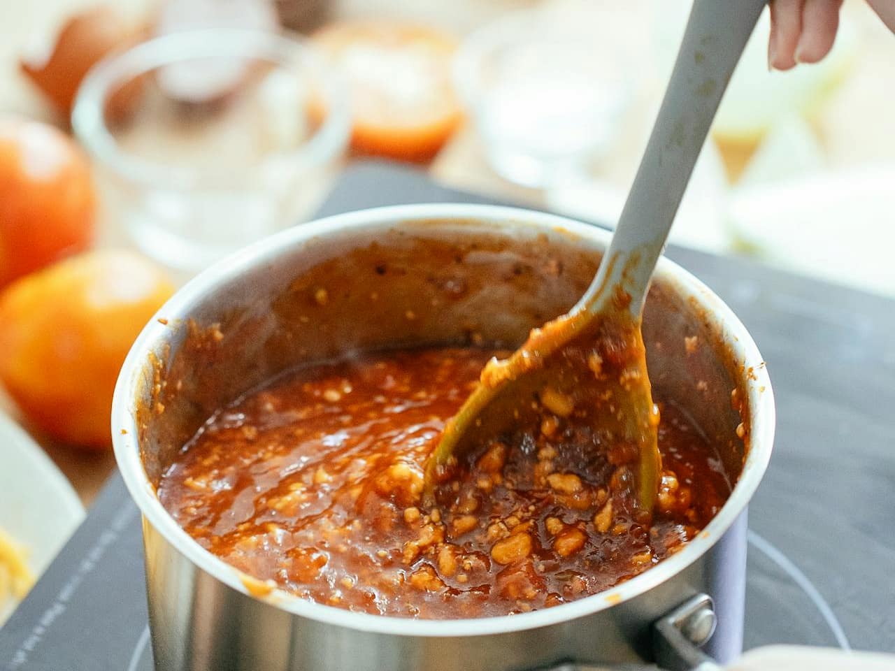 Tomato-based sauce with beans being stirred in a stainless steel pot