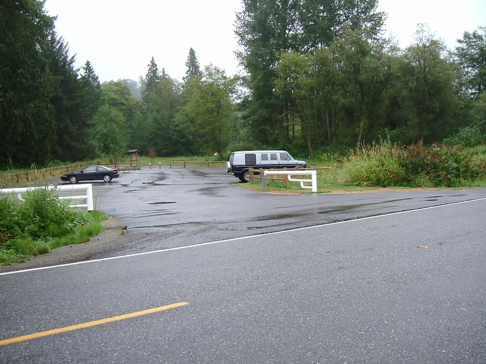 Trailhead parking lot at Centennial Trail in Washington with two vehicles and surrounding forest