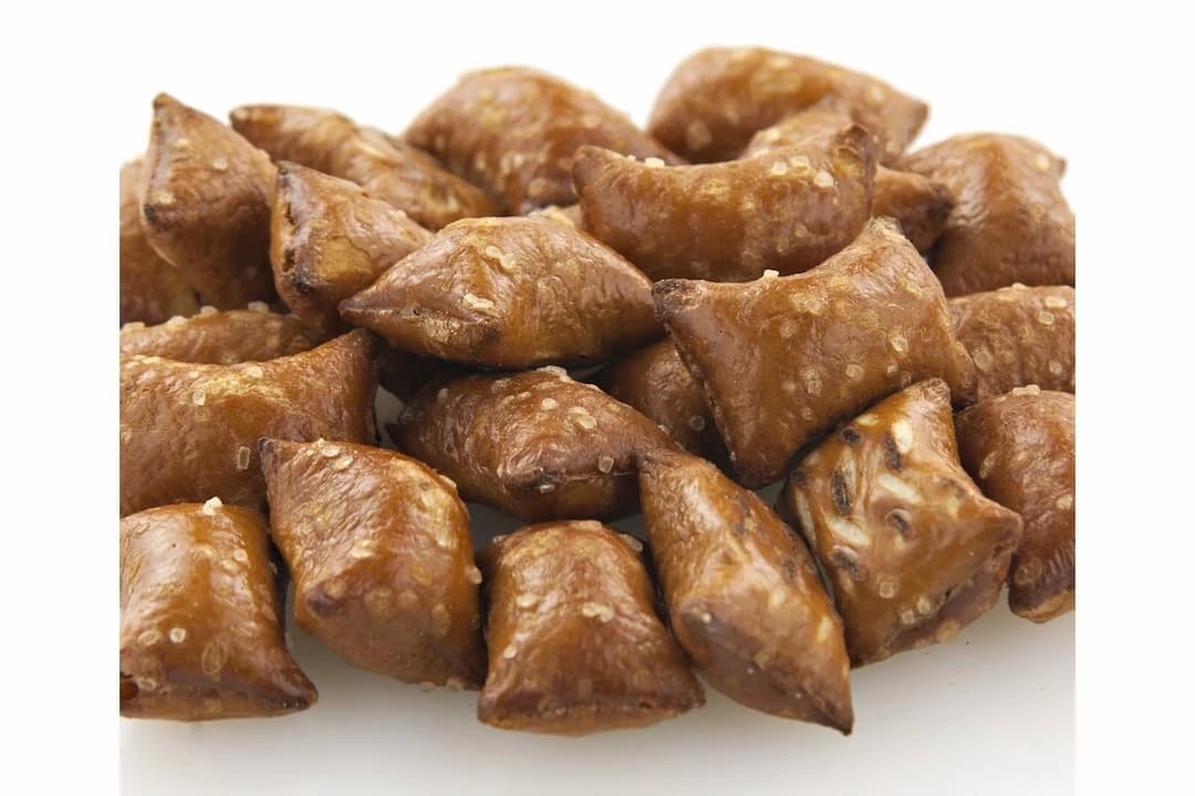 A pile of crunchy, salted pretzel nuggets filled with peanut butter on a white background