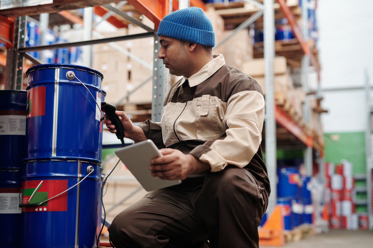 Warehouse worker scanning barcode on a blue 5-gallon bucket while holding a tablet