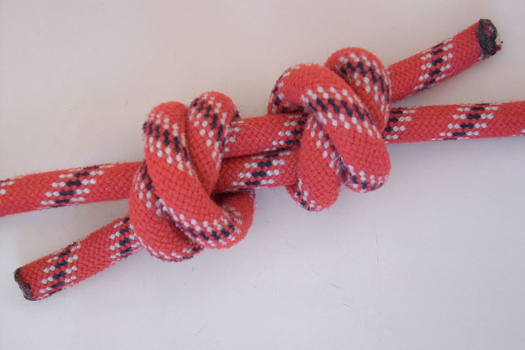  Red rope tied in a double fisherman's knot on a white surface