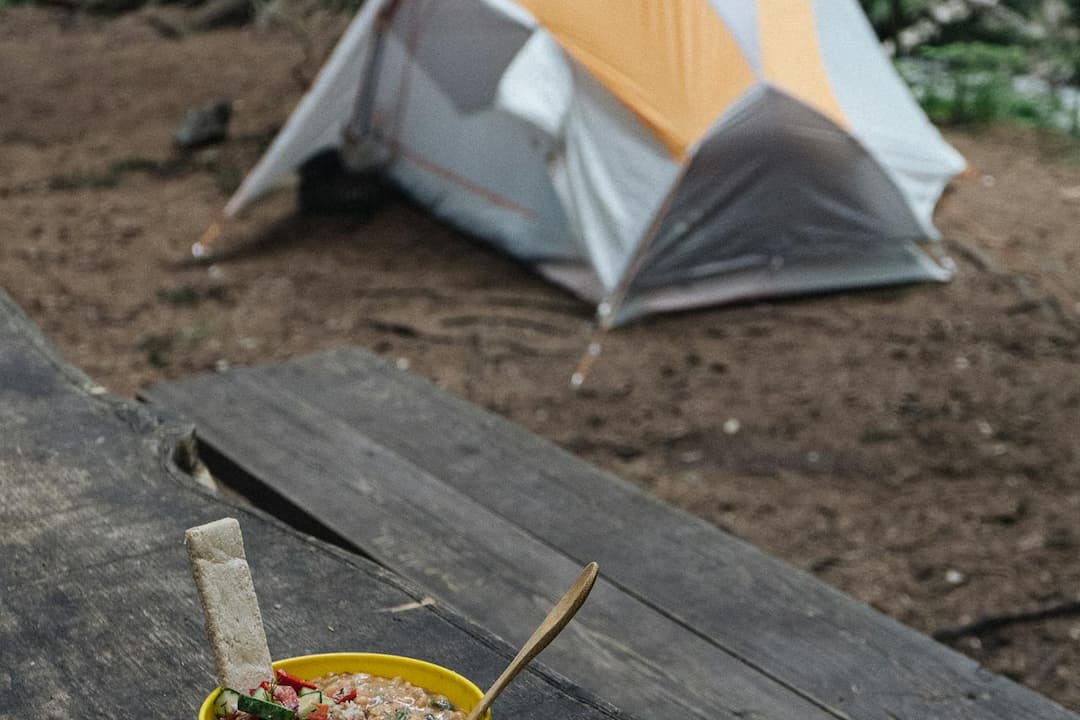 Yellow bowl filled with a colorful wild edible dish and a wooden spoon, placed on a weathered wooden surface