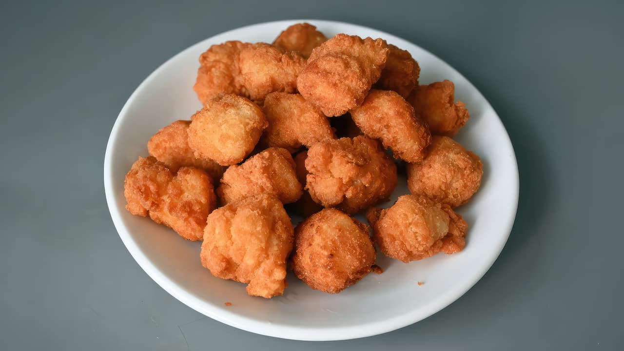 A plate of golden brown fried fish nuggets on a white dish